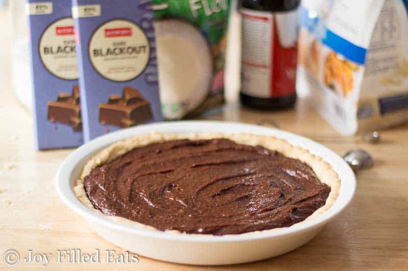 fudge brownie batter set in a white pie plate with low carb crust surrounded by ingredients in the background