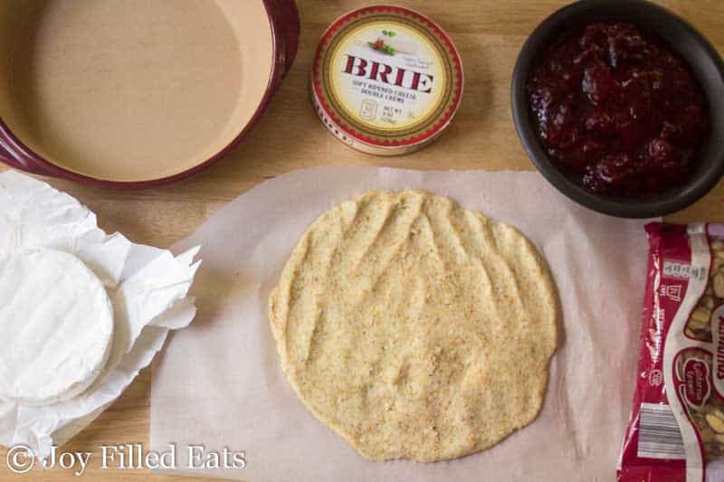 dough for baked brie rolled out into a circle shape surrounded by ingredients needed to assemble cranberry baked brie