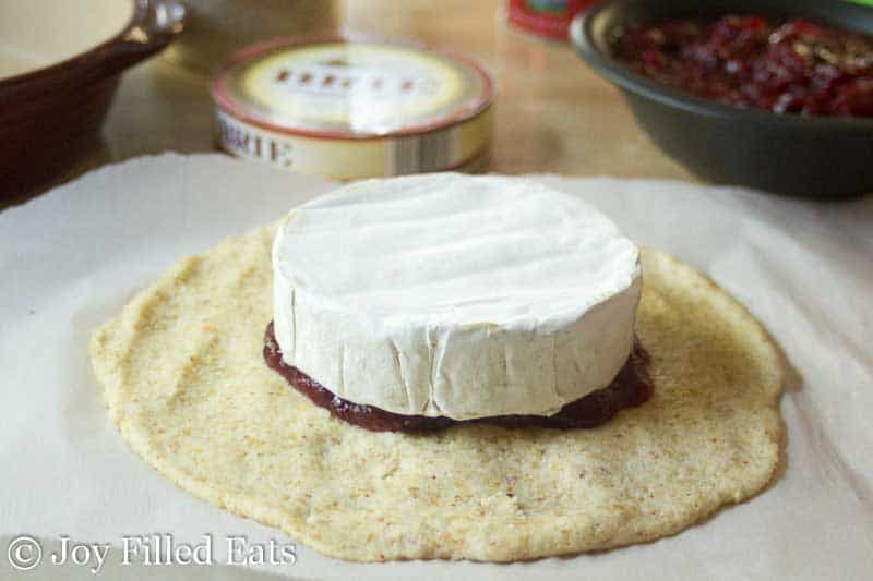 one round of brie cheese placed on top of a cranberry sauce spread onto rolled out dough