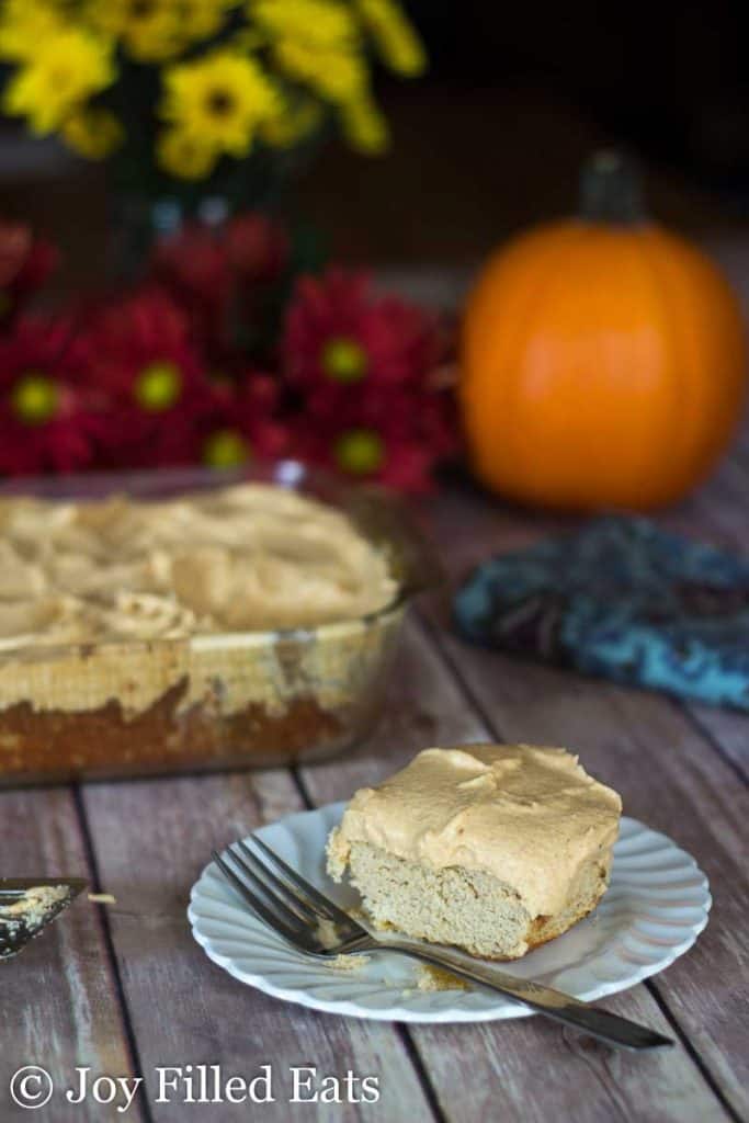 slice of coconut flour cake with pumpkin ricotta cream topping on a white plate with fork