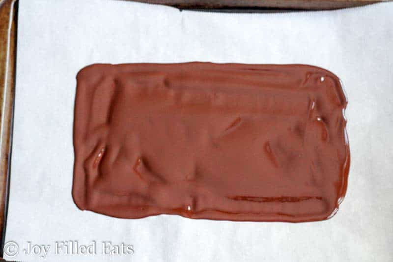 melted chocolate spread out in a rectangle shape on a piece of parchment from above