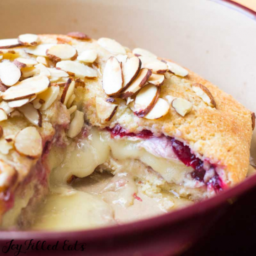 close up image of cranberry keto baked brie with large slice missing