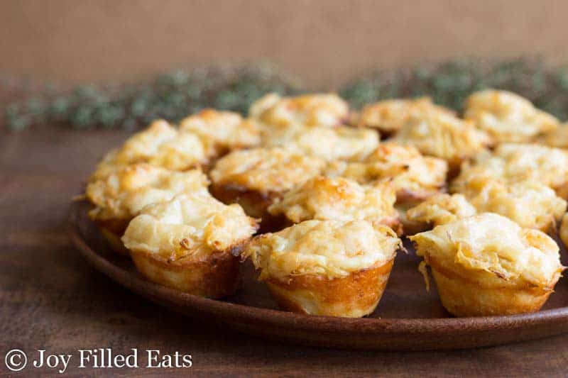 platter of French onion tartlets on a wooden plate