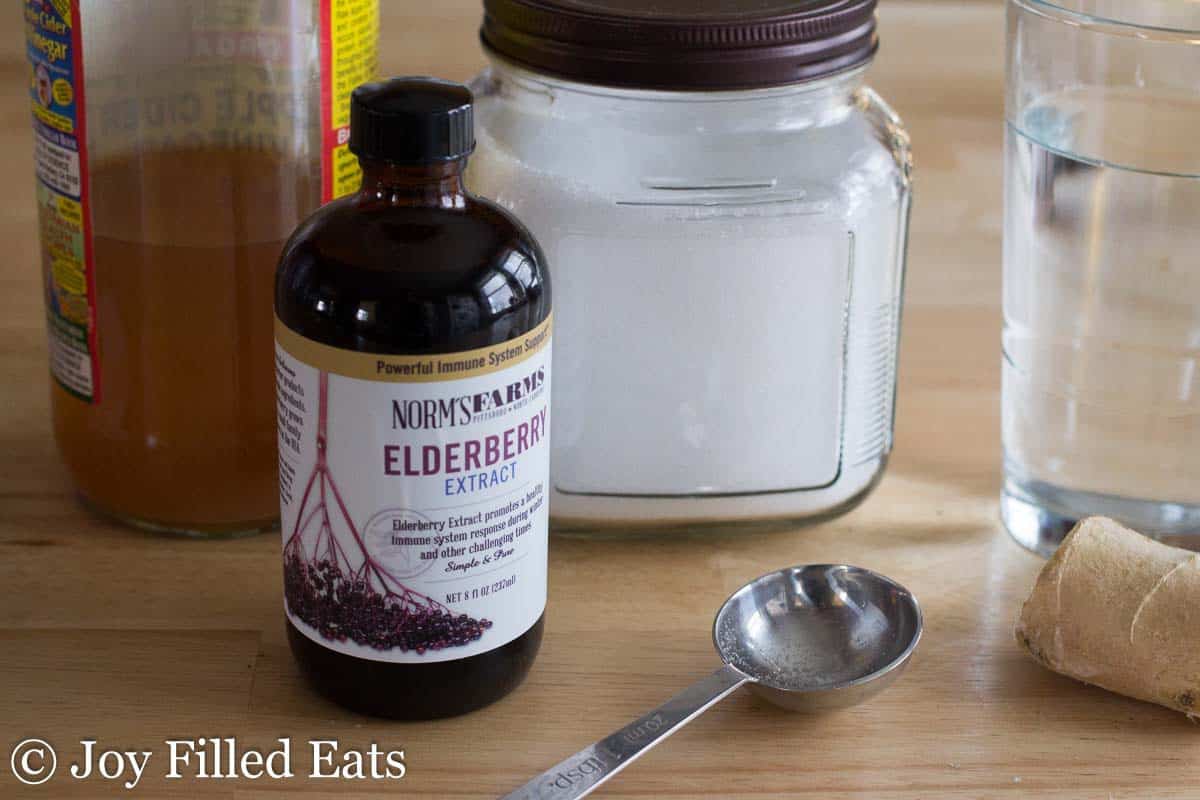 tablespoon set on a table surrounded by ingredients for Elderberry good girl moonshine