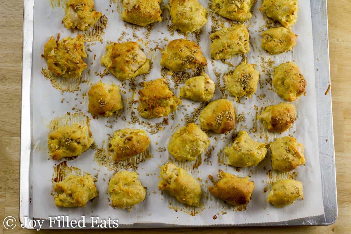 sesame chicken bites lined on a cookie sheet covered in parchment paper