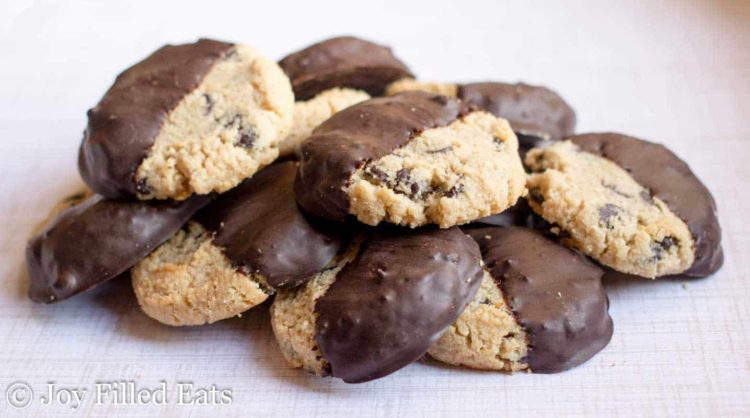 close up on pile of chocolate chip shortbread cookies, all half dipped in chocolate