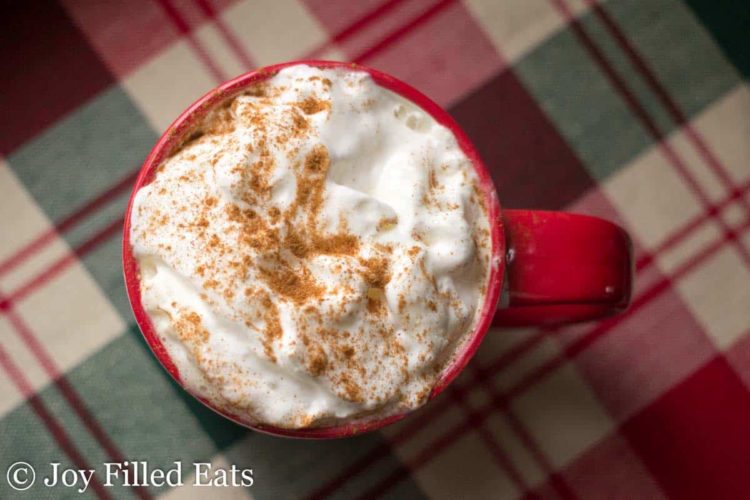 overhead view of cinnamon vanilla latte in a red mug topped with whipped cream