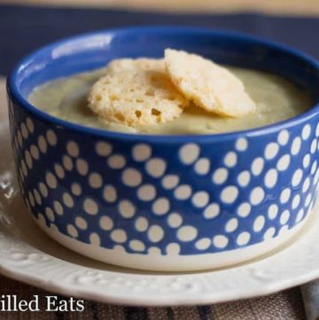 blue and white polka dot bowl filled with creamy garlic soup and topped with cheese croutons