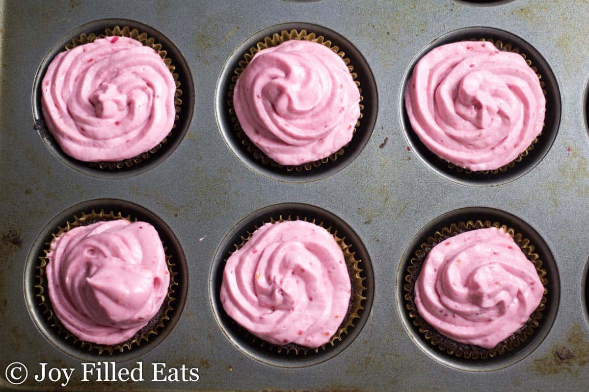 overhead view of chocolate champagne cupcakes with raspberry icing placed in a muffin tin