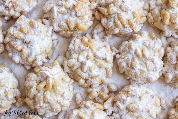 close up on keto pignoli cookies dusted in a powdered sweetener