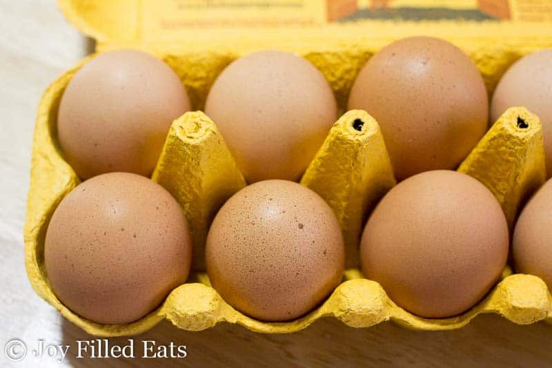overhead view of large brown eggs in a yellow carton