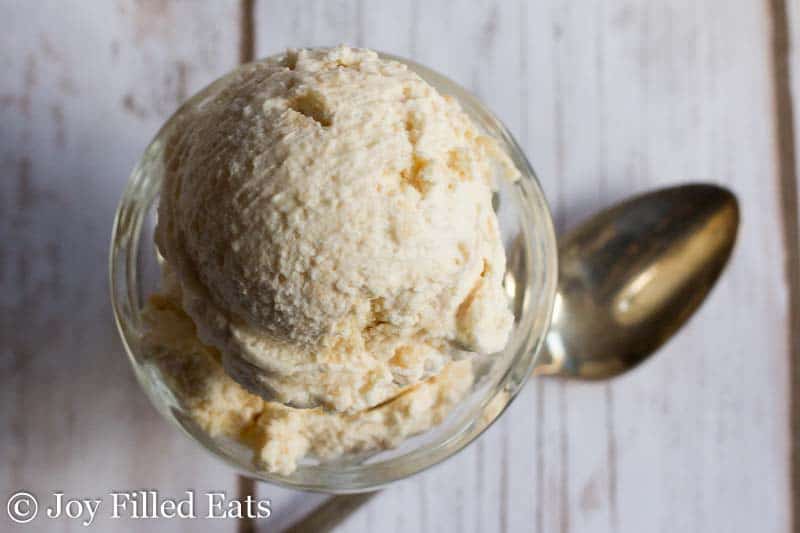 overhead view of scoop of salted caramel ice cream in glass with a spoon