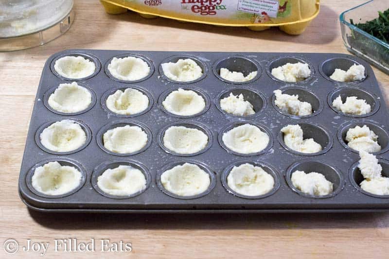 dough for mini quiches pressed and shaped into mini muffin tin