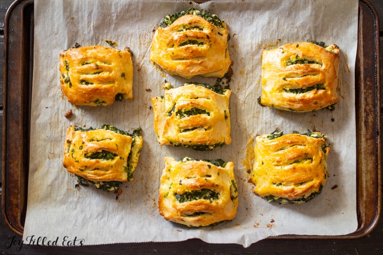 overhead view of spinach and feta pastries arranged on a parchment lined sheet pan