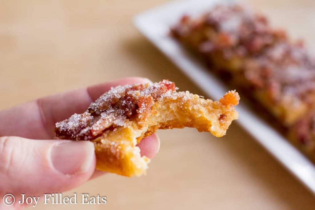 hand holding low carb maple bacon crack with large bite missing