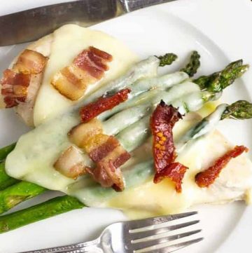 chicken and asparagus sheet pan dinner topped with bacon bits on a plate with fork