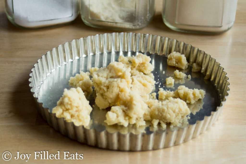 crust of almond tart balled into pie tin before being spread across the bottom