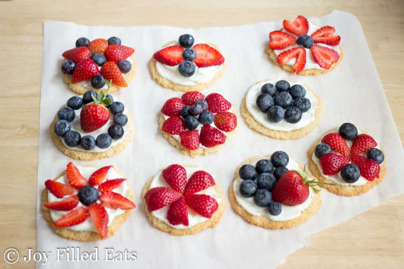 decorated mini fruit pizza cookies lined on parchment paper