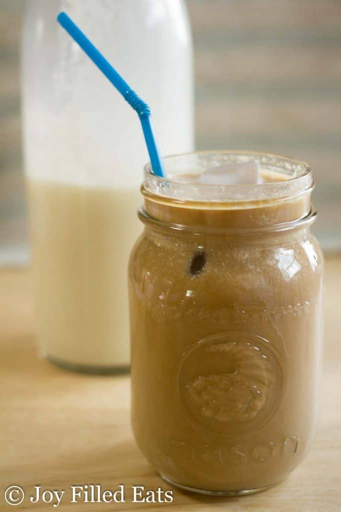 mason jar of iced coffee with monkfruit coffee cream served with a blue straw
