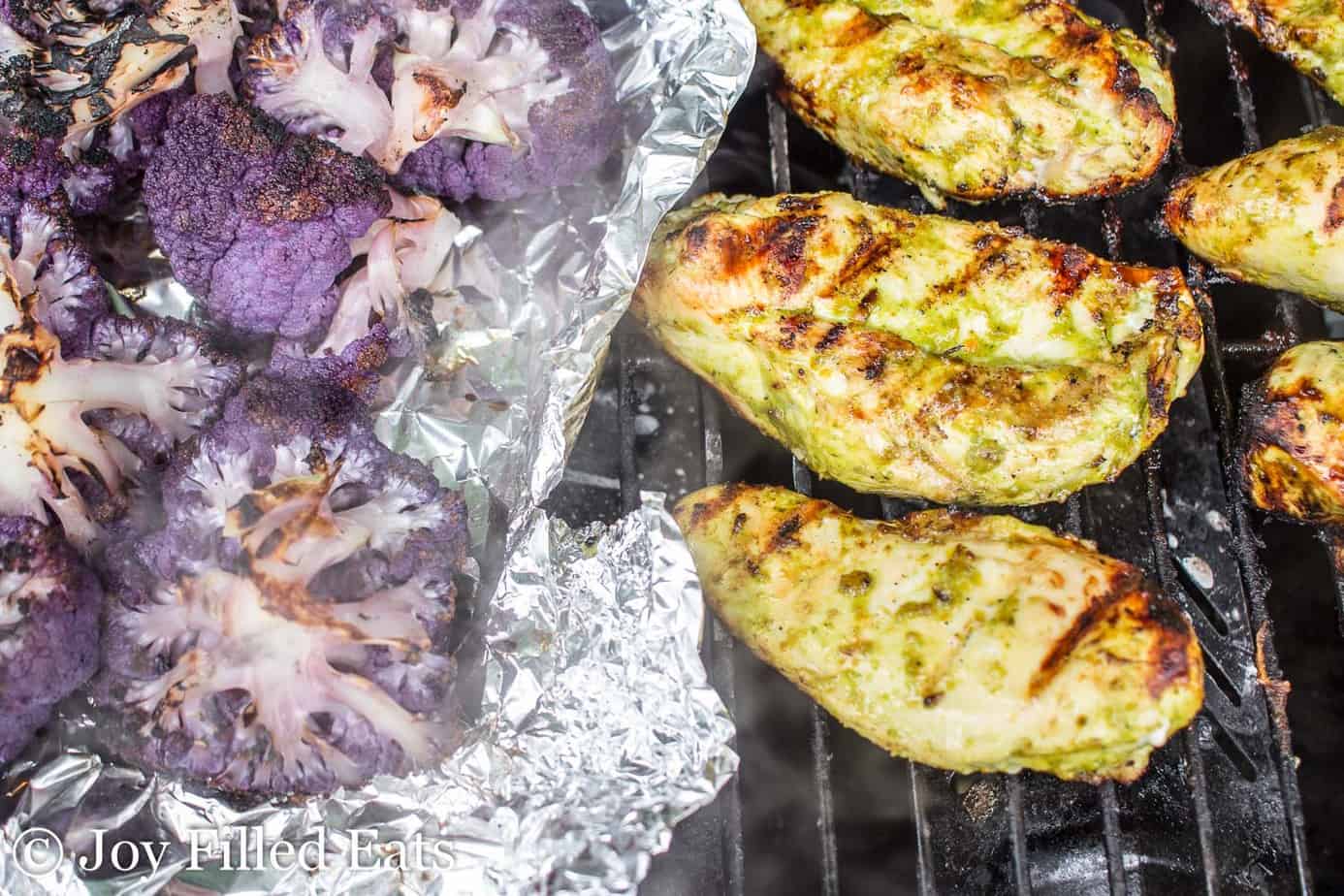 citrus basil grilled chicken placed on a grill next to purple cauliflower in aluminum