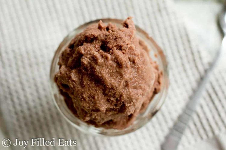 overhead view on chocolate cream Italian ice scooped in small glass bowl placed next to spoon