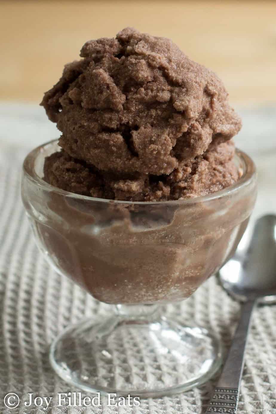 close up on chocolate cream Italian ice scoop in small glass bowl placed next to spoon