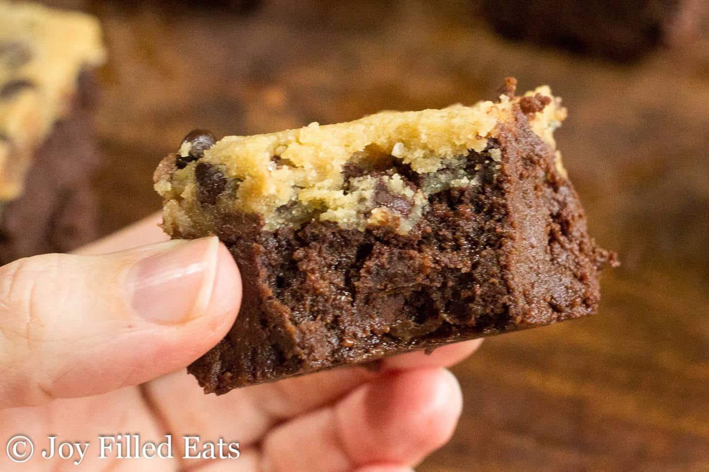hand holding a chocolate chip cookie dough brownie with large bite missing