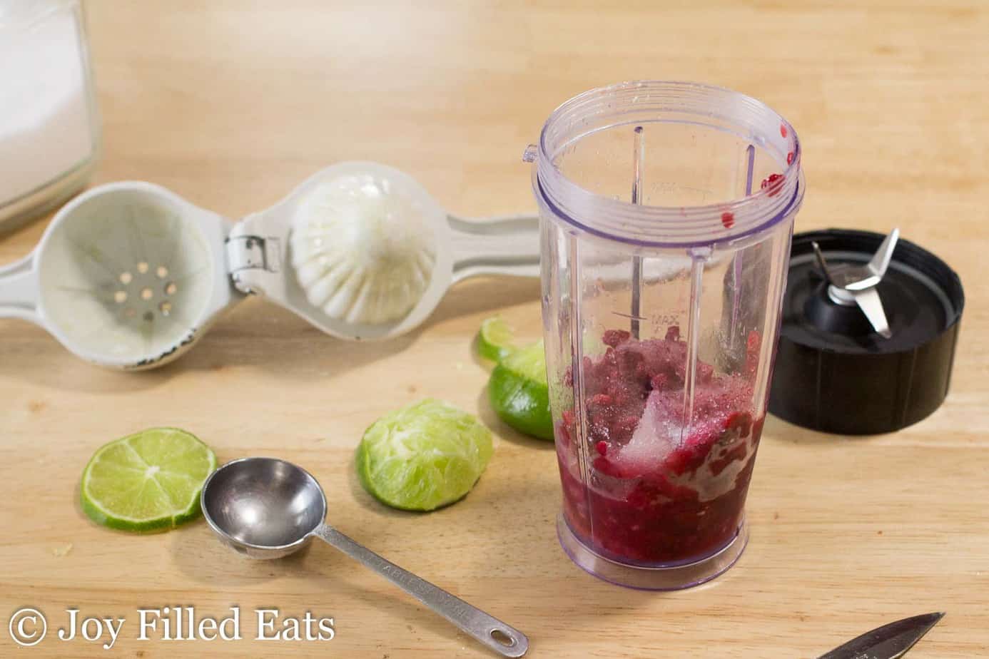 small blender surrounded by raspberry lime soda ingredients and needed utensils
