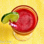 overhead view of sparkling raspberry lime soda with a lime slice on the rim with paper straw