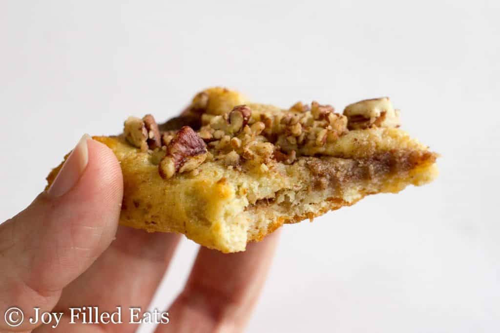 hand holding a Pecan Danish with large bite missing