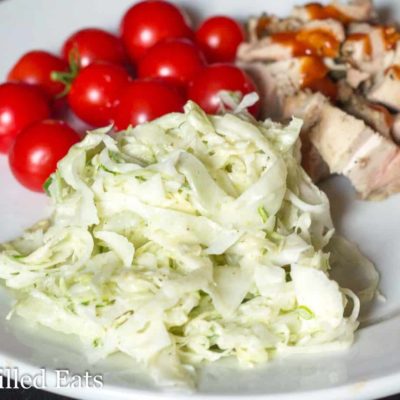 coleslaw with fennel on a plate with cherry tomatoes and BBQ sauced meat