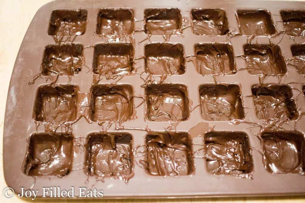 melted chocolate poured into bottom of square molds on tray