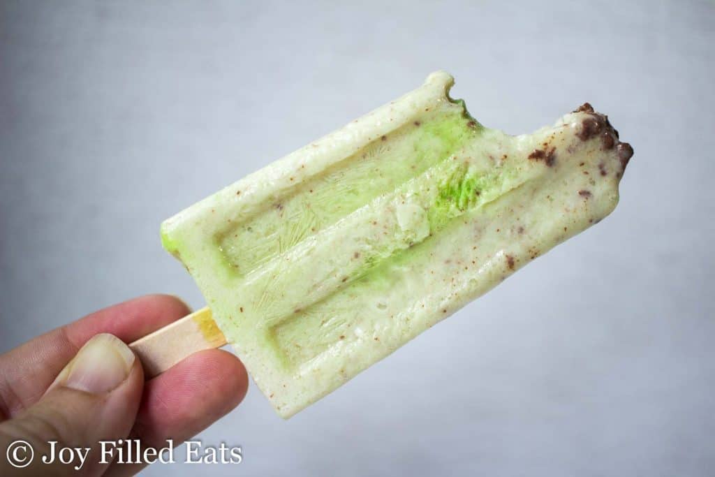 hand holding a mint chocolate chip ice cream bar with bite missing