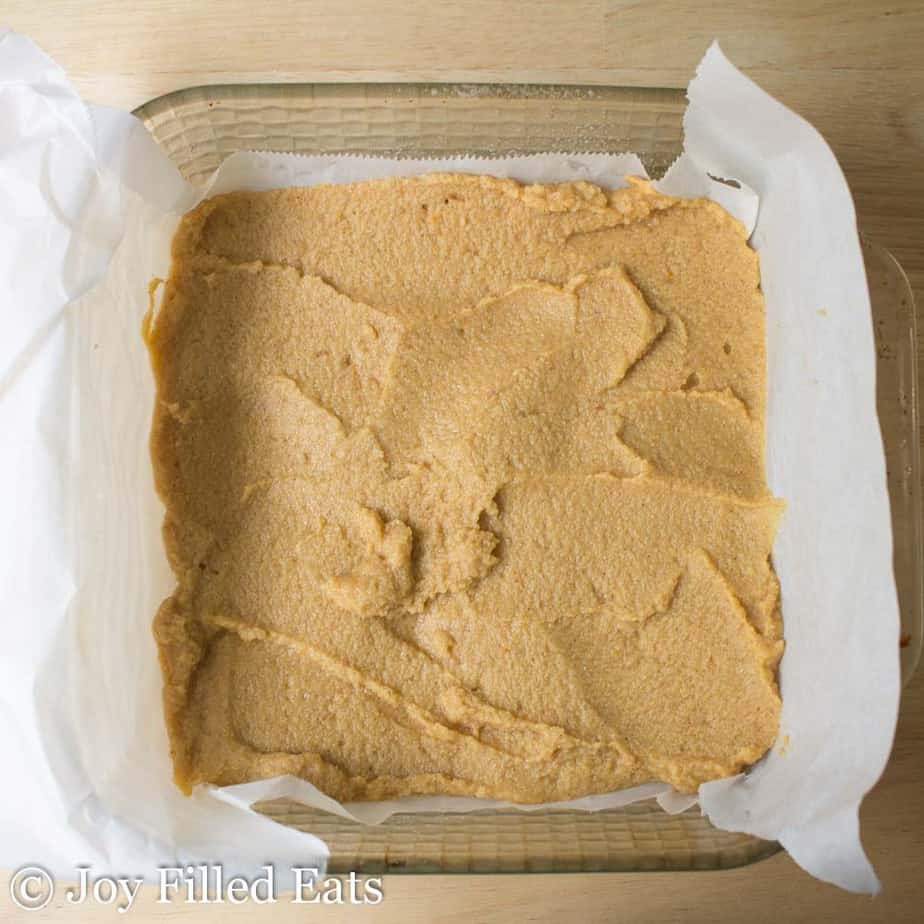 mini pumpkin cake roll batter spread into parchment lined baking dish