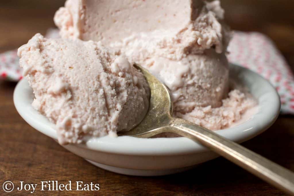spoonful of strawberry ricotta ice cream laying on a bowl full of more ice cream
