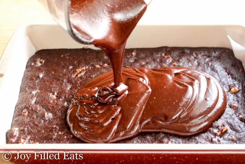 melted chocolate being poured onto homemade Little Debbie Fudge Brownie base