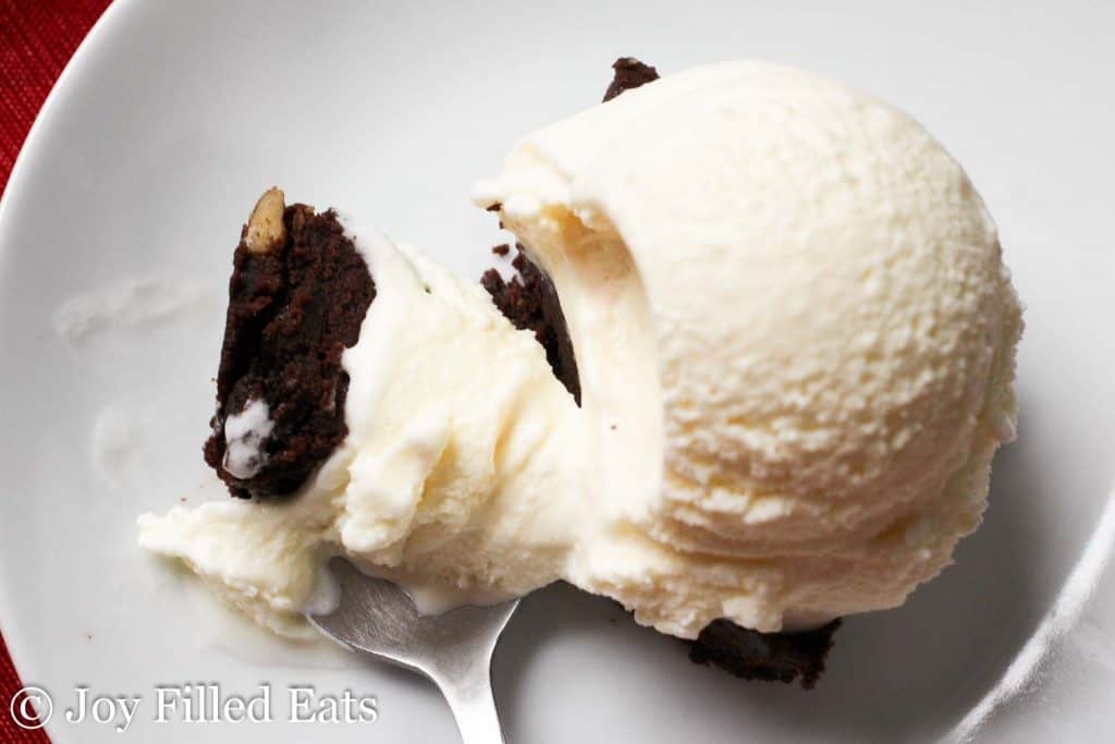 overhead view of spoon full of ice cream and a piece of brownie next to a large scoop of ice cream