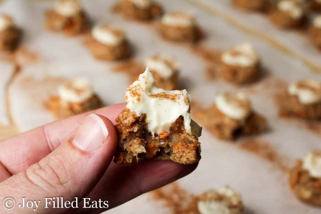 hand holding mini carrot cake cookie with cream cheese frosting