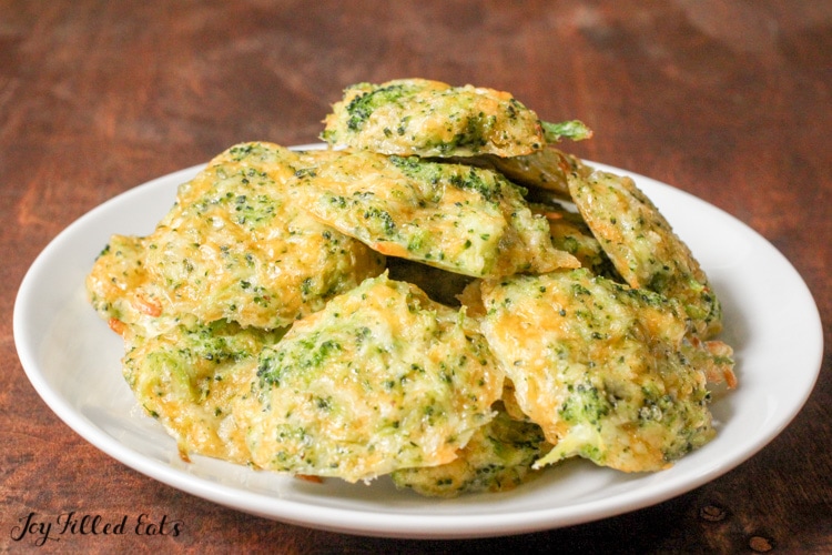 A white plate on a dark wood surface with a pile of Broccoli Nuggets