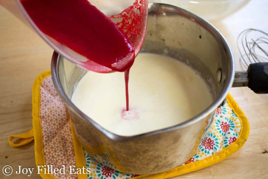 raspberry puree being poured into sauce pan of panna cotta gelatin