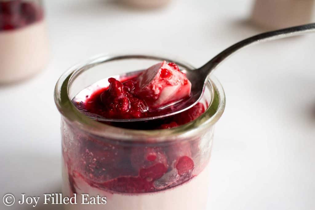 jar of raspberry panna cotta with spoon inside scooping a bite