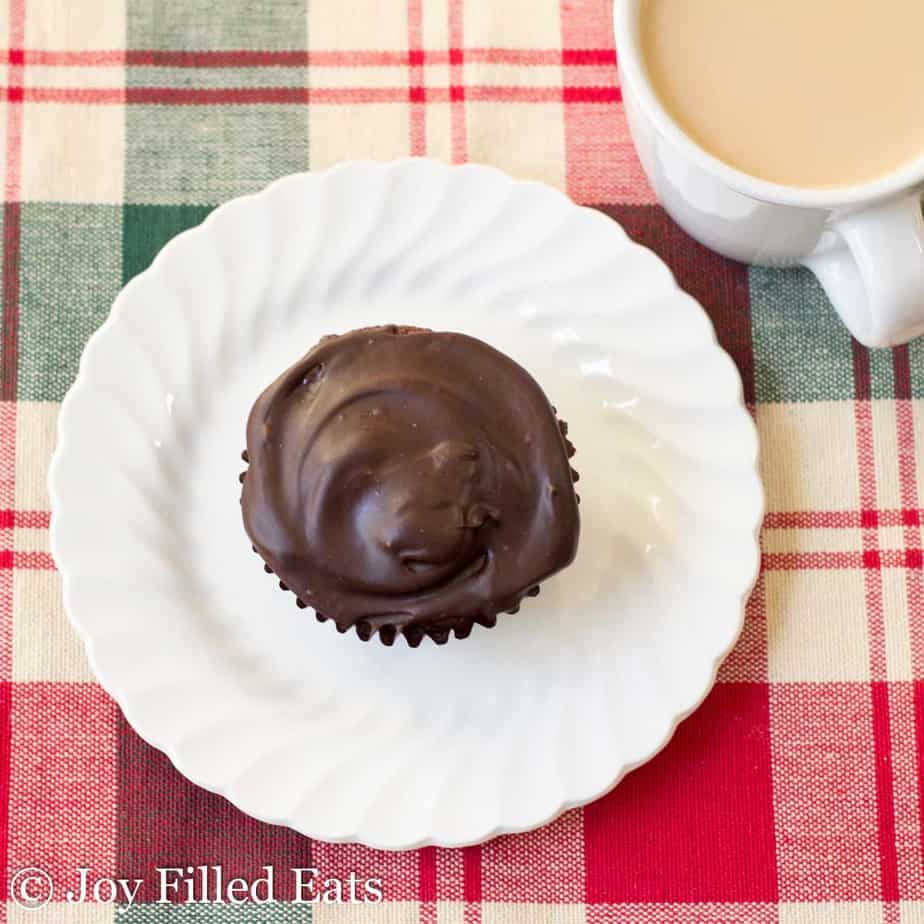 one dark chocolate peppermint cupcake sitting on a white plate next to a cup of coffee from above