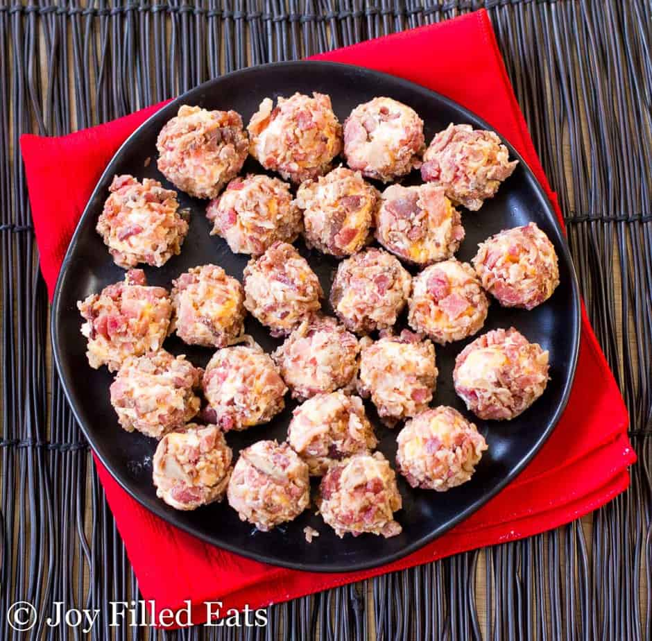 overhead view of bacon cheddar mini cheese balls on a black plate set on a red napkin