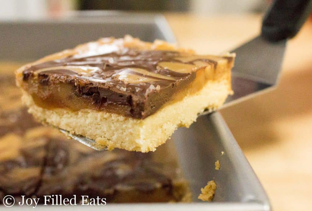 Salted Caramel shortbread Square being lifted by pie server from baking dish