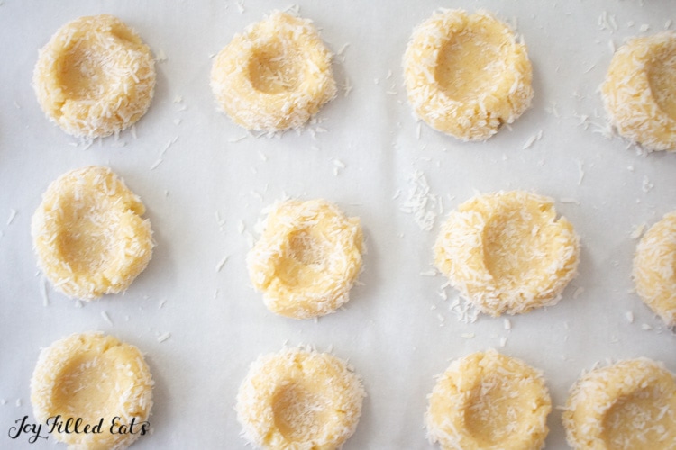 thumbprint cookies coated in coconut flakes from above on parchment paper