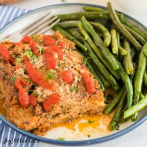 serving of keto turkey meatloaf with a side of green beans on a plate with fork close up
