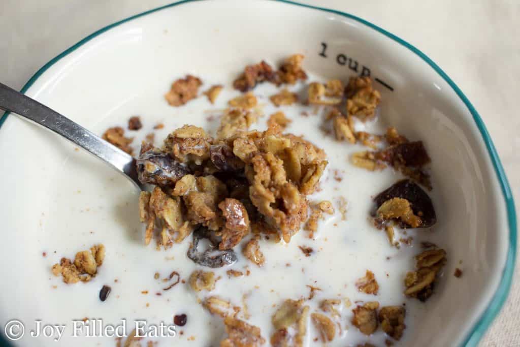 spoonful of healthy granola in bowl with type of milk