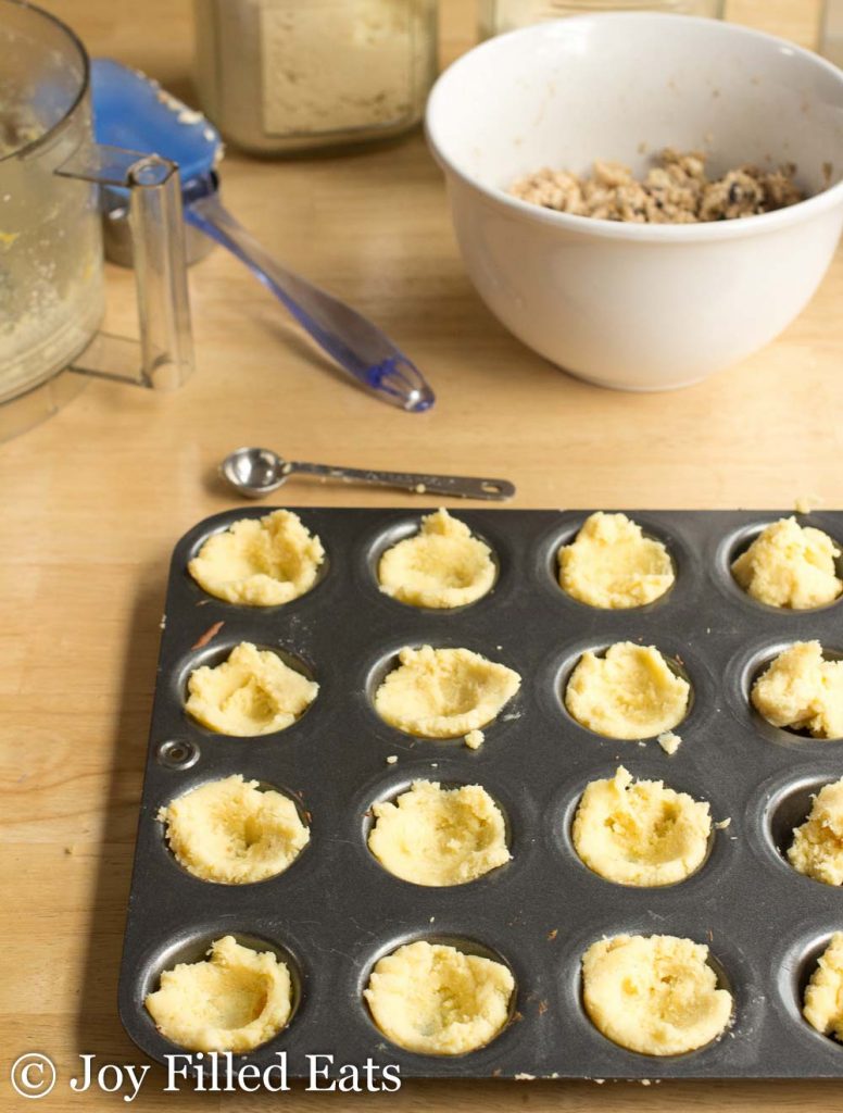 dough for appetizer bites placed in a mini muffin tin and shaped into cups