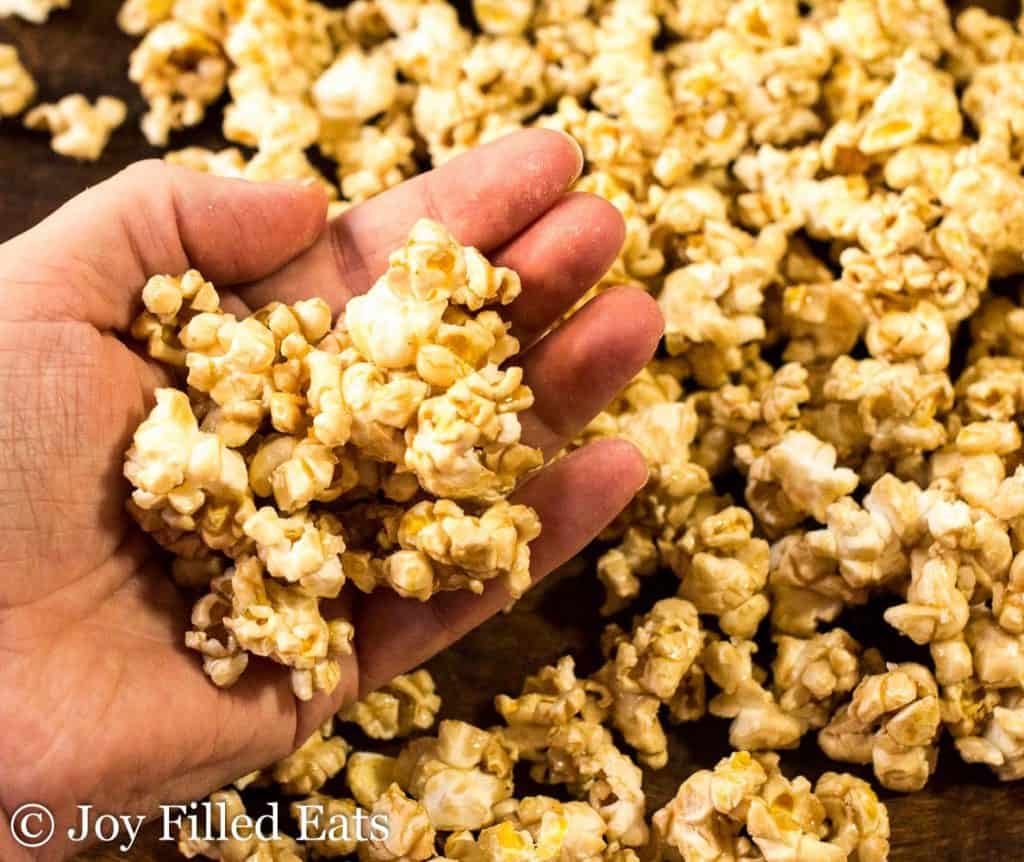 A hand holding salted caramel popcorn.