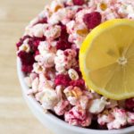 bowl of raspberry lemonade popcorn topped with dried raspberry pieces and a lemon slice